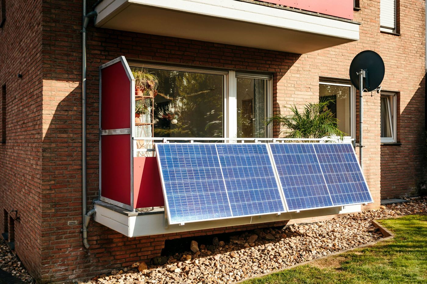 Balcón de un edificio de ladrillo con paneles solares de un kit de balcón colgados de la barandilla